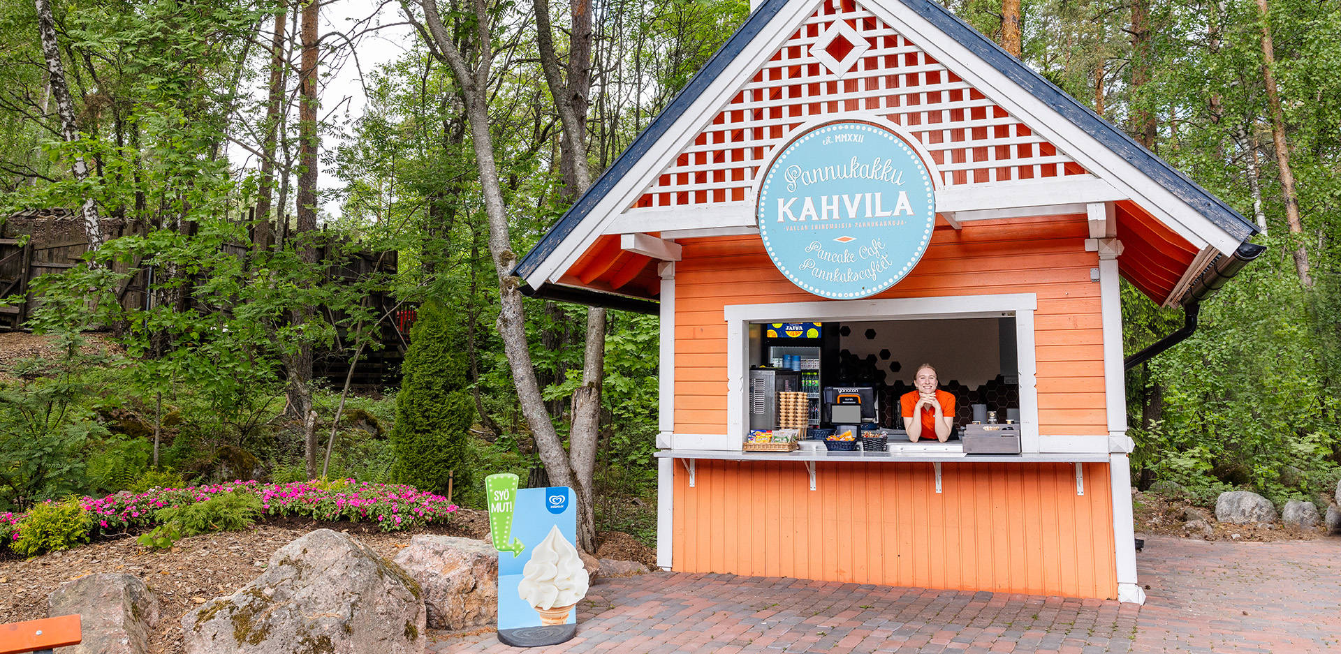 Pannukakkukahvilan myyjä iloisena kioskin sisällä.