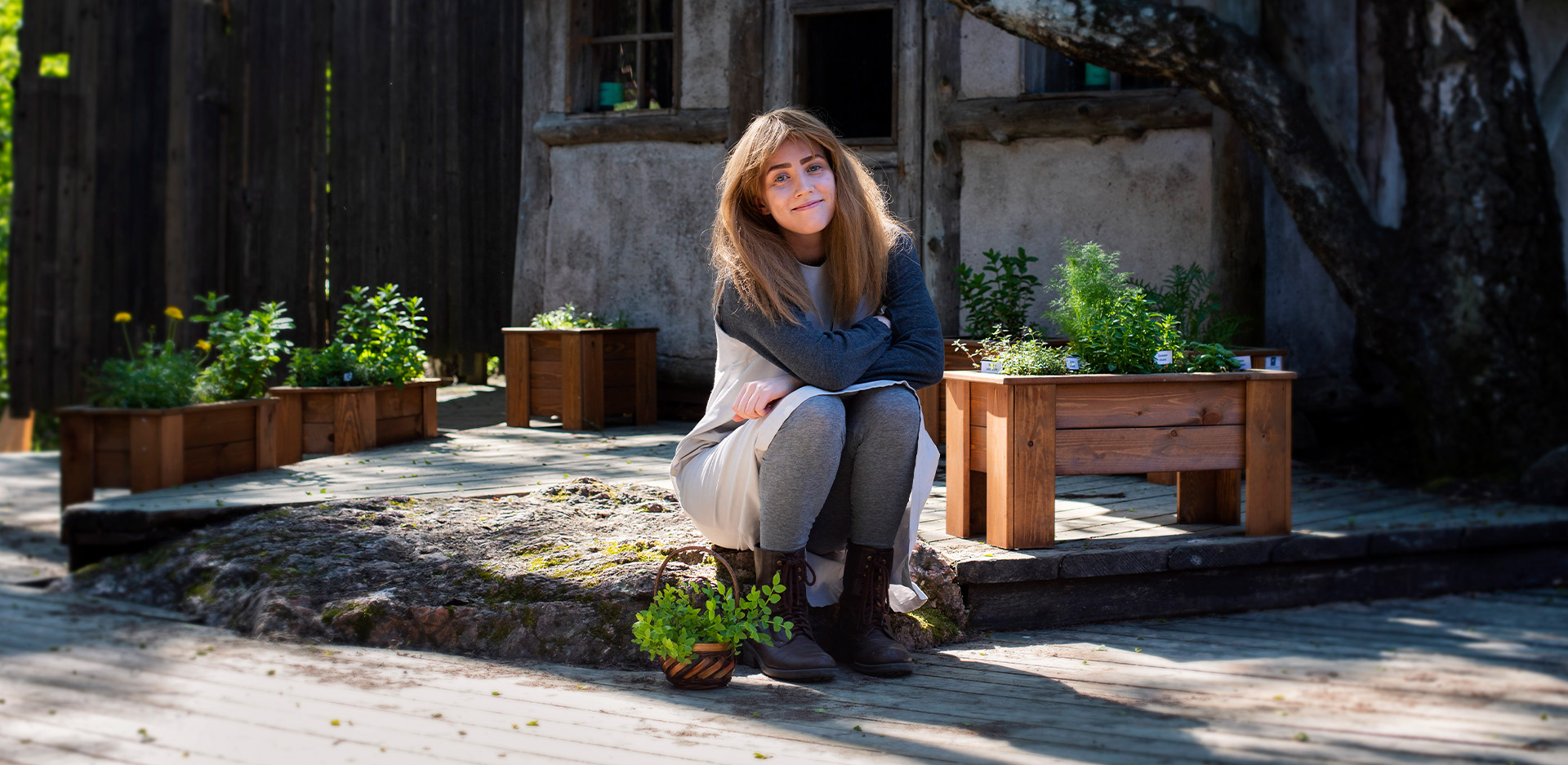 Aliisa istuu yrttitarhassa.