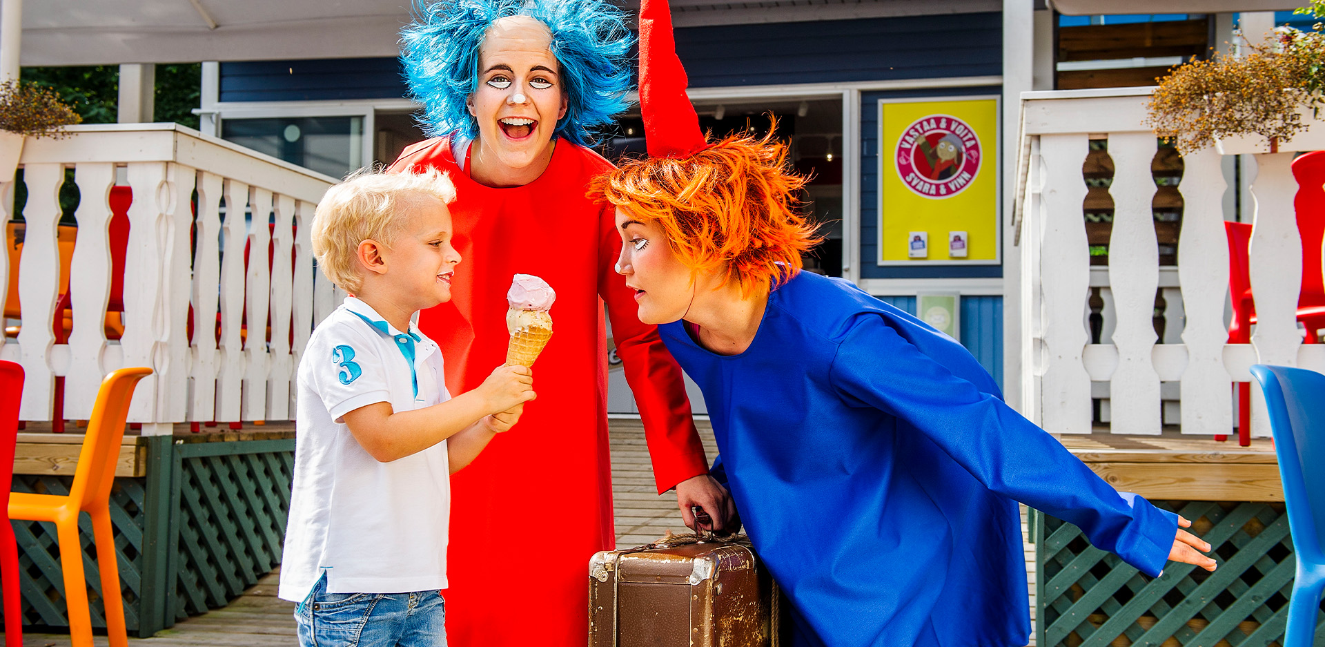 Tiuhti ja Viuhti syövät jäätelöä Tiuhtin ja Viuhtin jäätelöbaarin edessä.